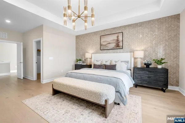 a spacious bedroom with a bed a lamp and a chandelier