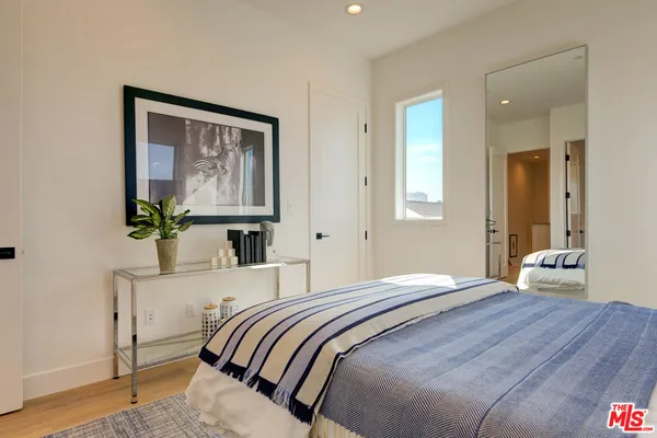 a bedroom with a bed painting on wall and a potted plant