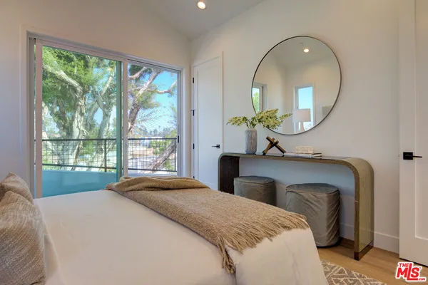 a bedroom with a bed mirror and a large window