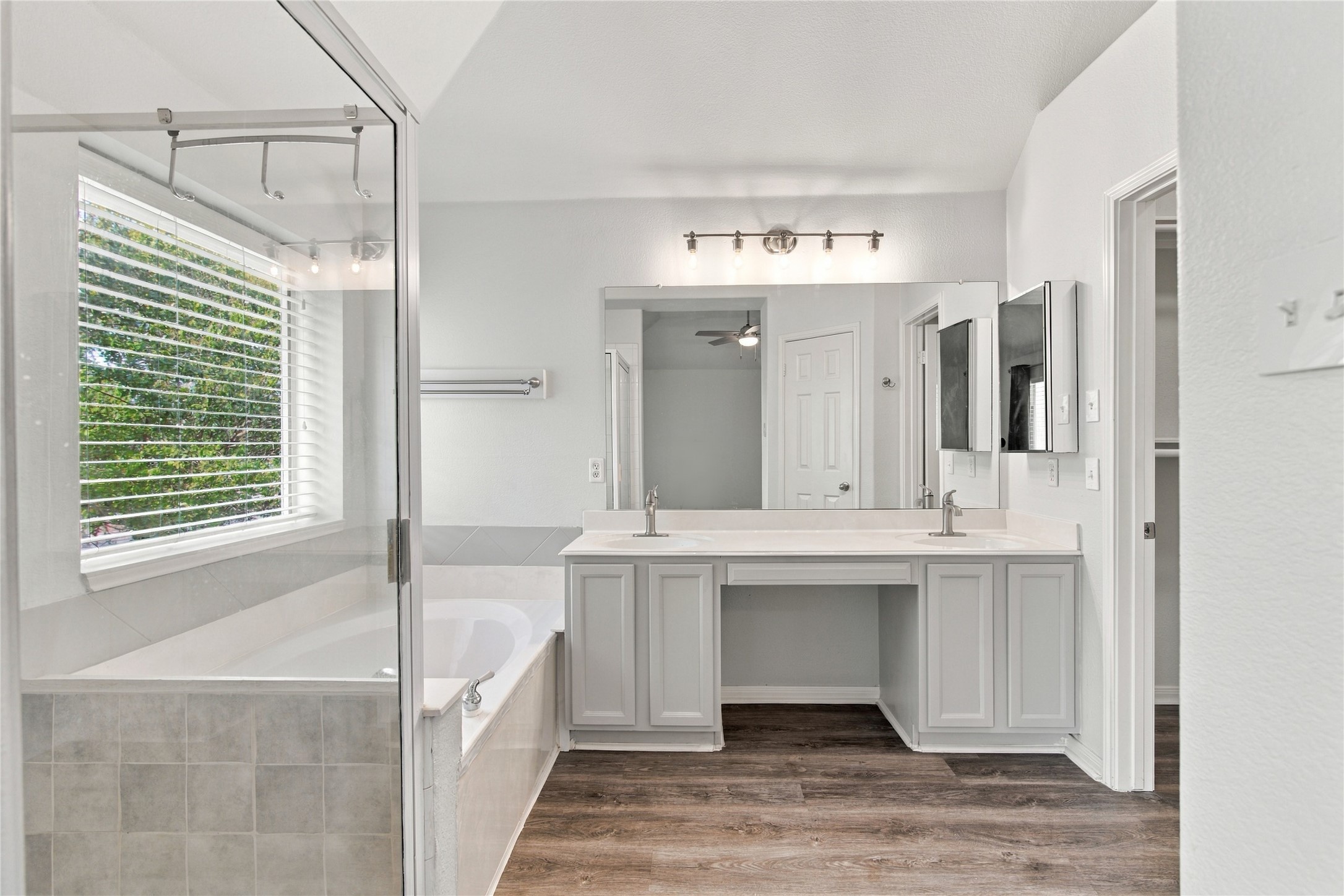 910 Point Run Drive Pflugerville, TX 78660 - Photo 18 of 39 A spacious double vanity and soaking tub highlight this master bathroom with wood-look flooring.