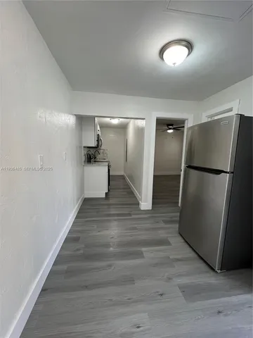 a kitchen with a refrigerator and a wooden floor