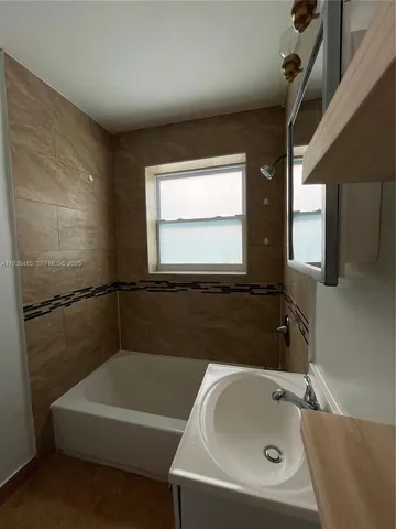 a bathroom with a tub sink and mirror