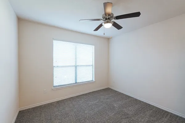 an empty room with a window and a fan