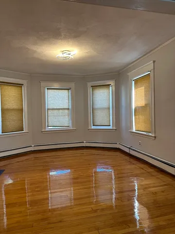 a view of an empty room with window and wooden floor