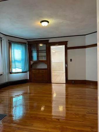 a view of an empty room with window and wooden floor