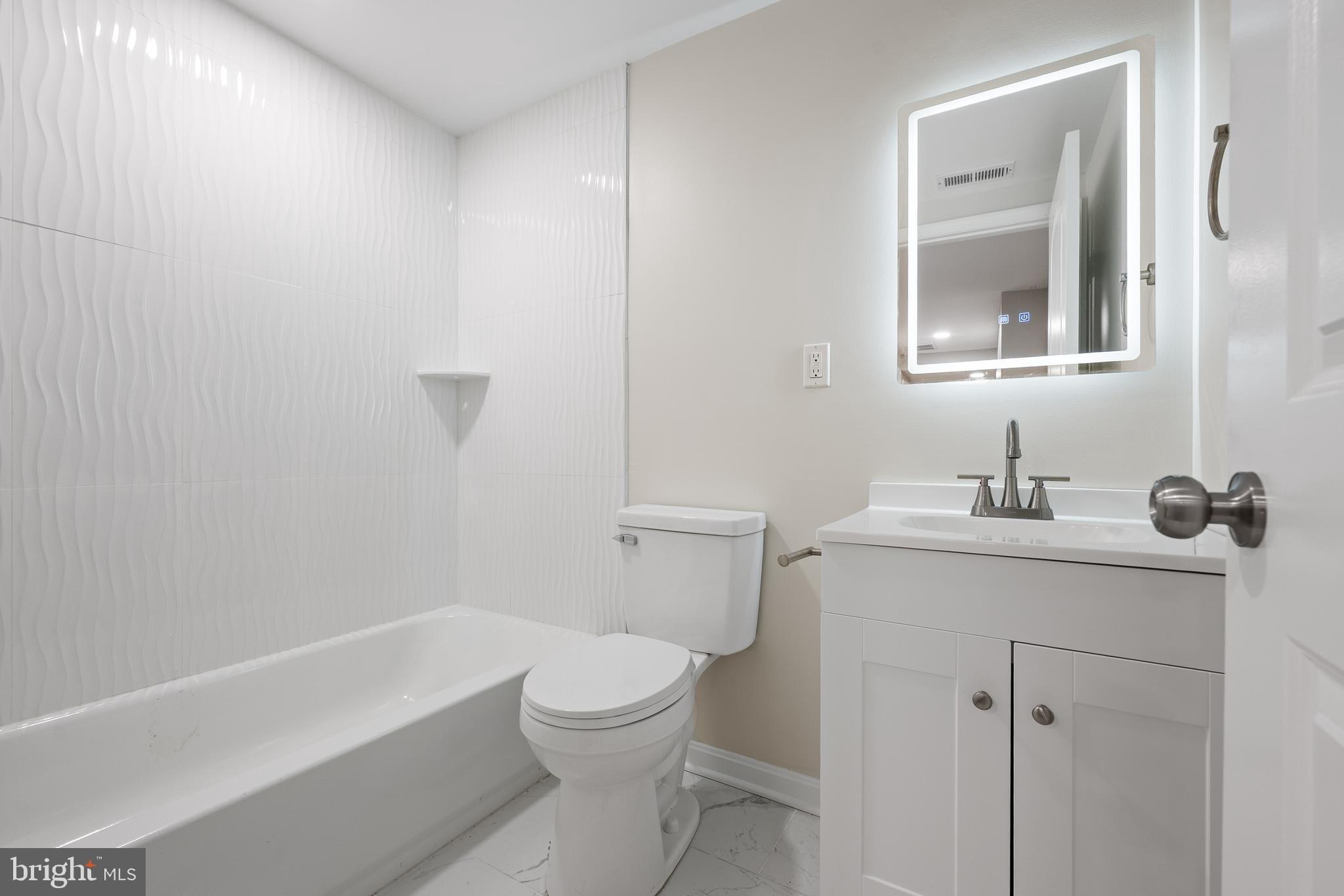 1358 Towson Street Baltimore, MD 21230 - Photo 29 of 39 a bathroom with a toilet a sink a mirror and vanity