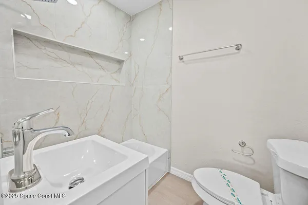 a bathroom with a sink a toilet and shower