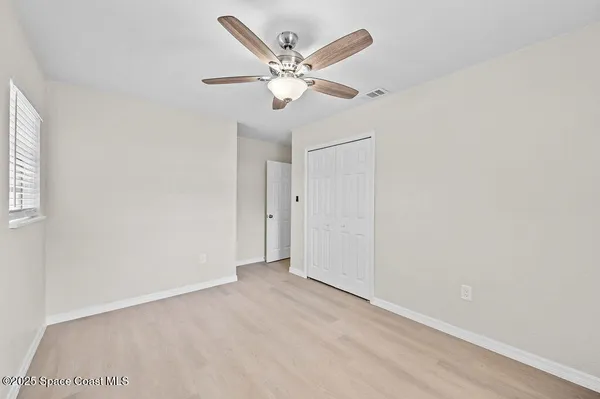 a view of an empty room with window and a ceiling fan