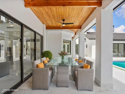a living room with patio furniture and potted plants