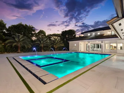 a front view of a house with swimming pool and trees