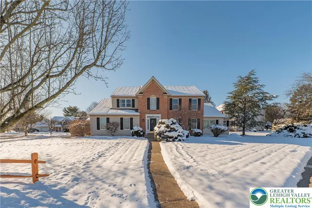 a front view of a house with a yard covered in snow