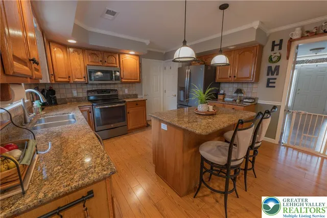 a kitchen with stainless steel appliances granite countertop a stove top oven a sink a dining table and chairs with wooden floor