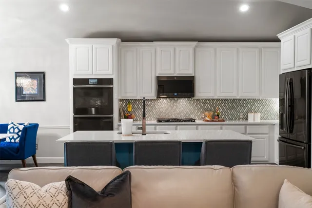 a kitchen with stainless steel appliances granite countertop a refrigerator a stove a sink a stove and white cabinets