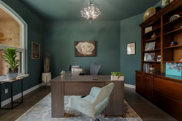 a work room with furniture a bookshelf and a window