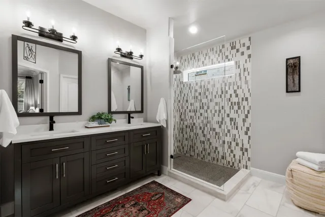 a bathroom with a double vanity sink mirror and shower