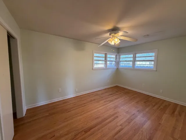a view of an empty room with window and wooden floor