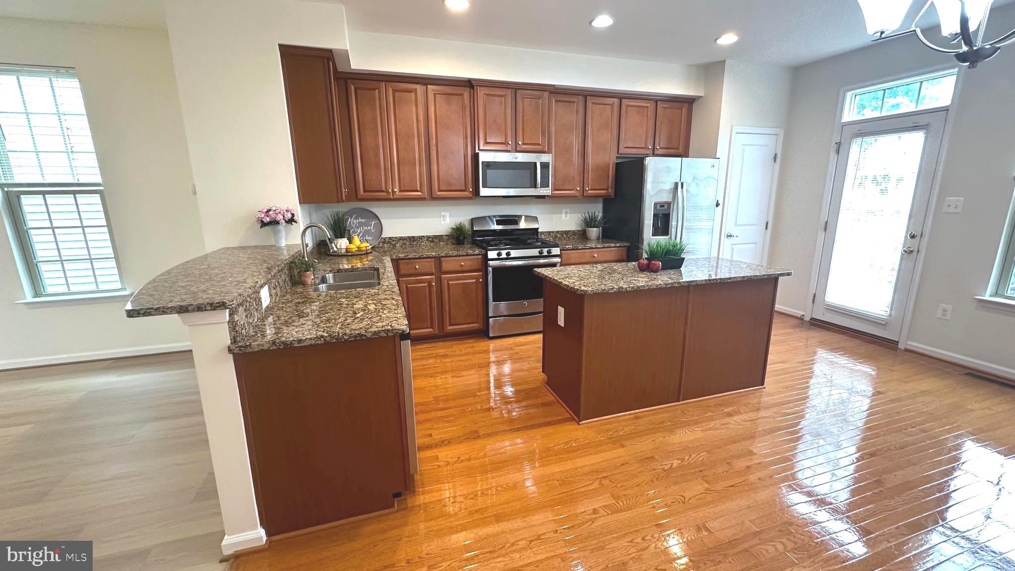7343 Old Calvary Road Hanover, MD 21076 - Photo 14 of 35 a kitchen with stainless steel appliances granite countertop a stove top oven a sink dishwasher and a refrigerator with wooden floor