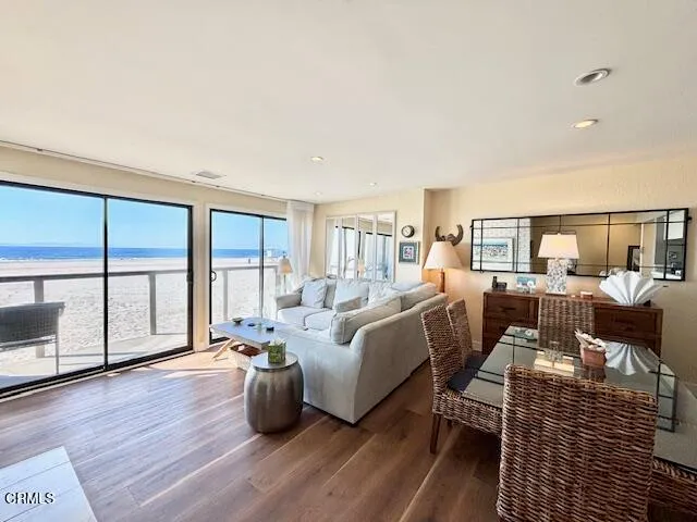 a living room with furniture large windows and wooden floor