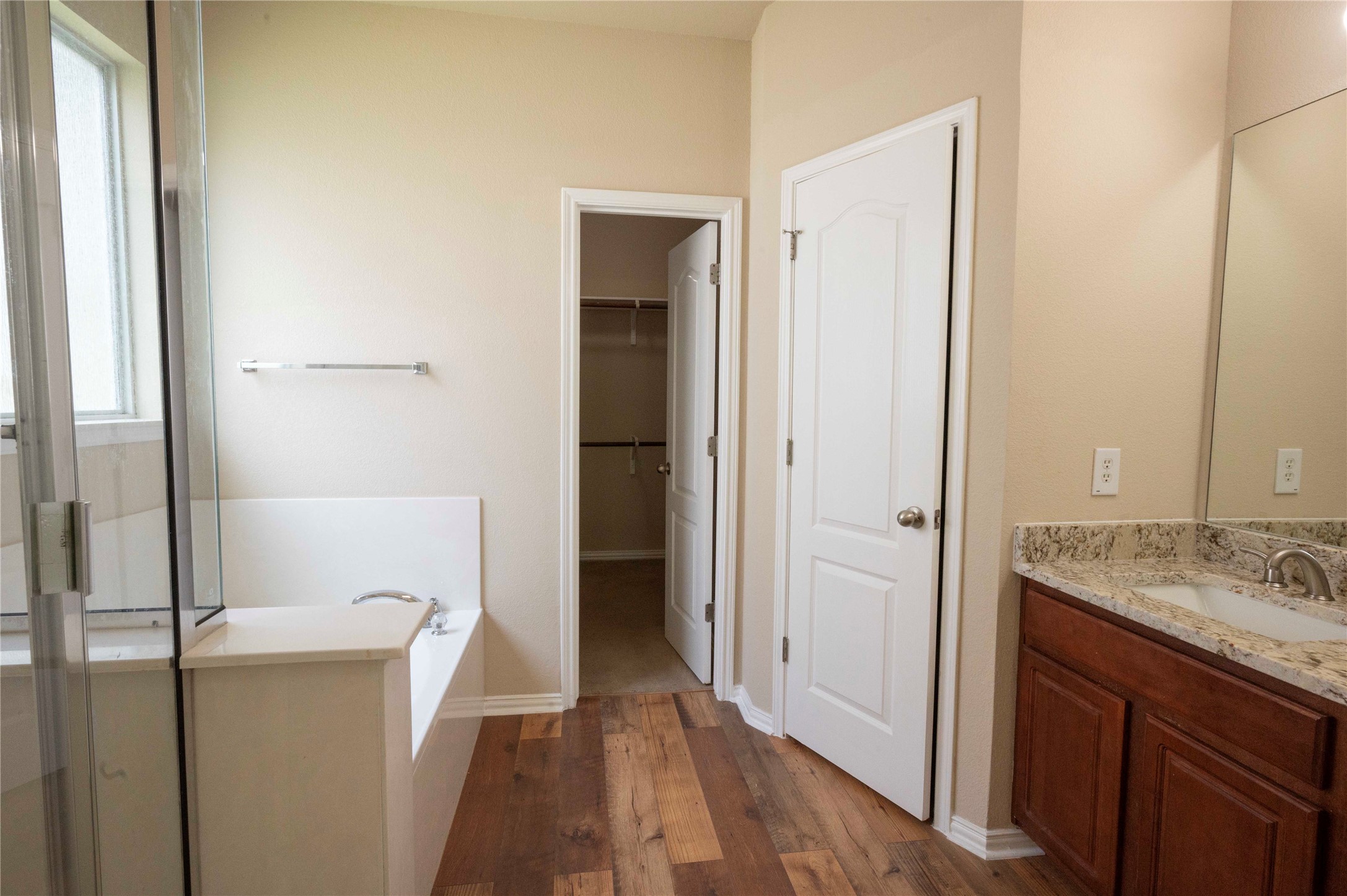 2070 Intrepid Drive Buda, TX 78610 - Photo 12 of 31 Indulge in a tranquil primary bathroom, complete with a soaking tub and elegant wood-style flooring.