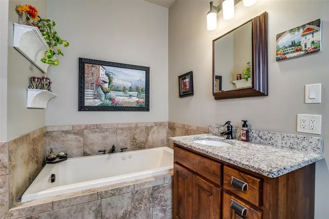 a bathroom with a granite countertop tub sink and mirror