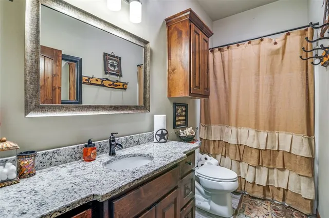 a bathroom with a granite countertop sink a toilet and shower curtain