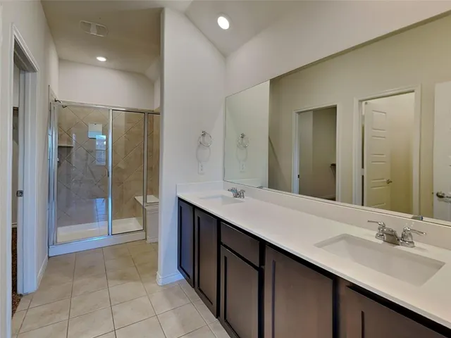 a bathroom with a double vanity sink mirror and shower
