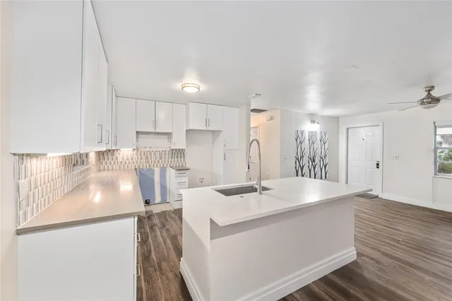 a kitchen with granite countertop a stove a sink and white cabinets with wooden floor