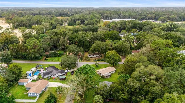 an aerial view of residential houses with outdoor space and trees