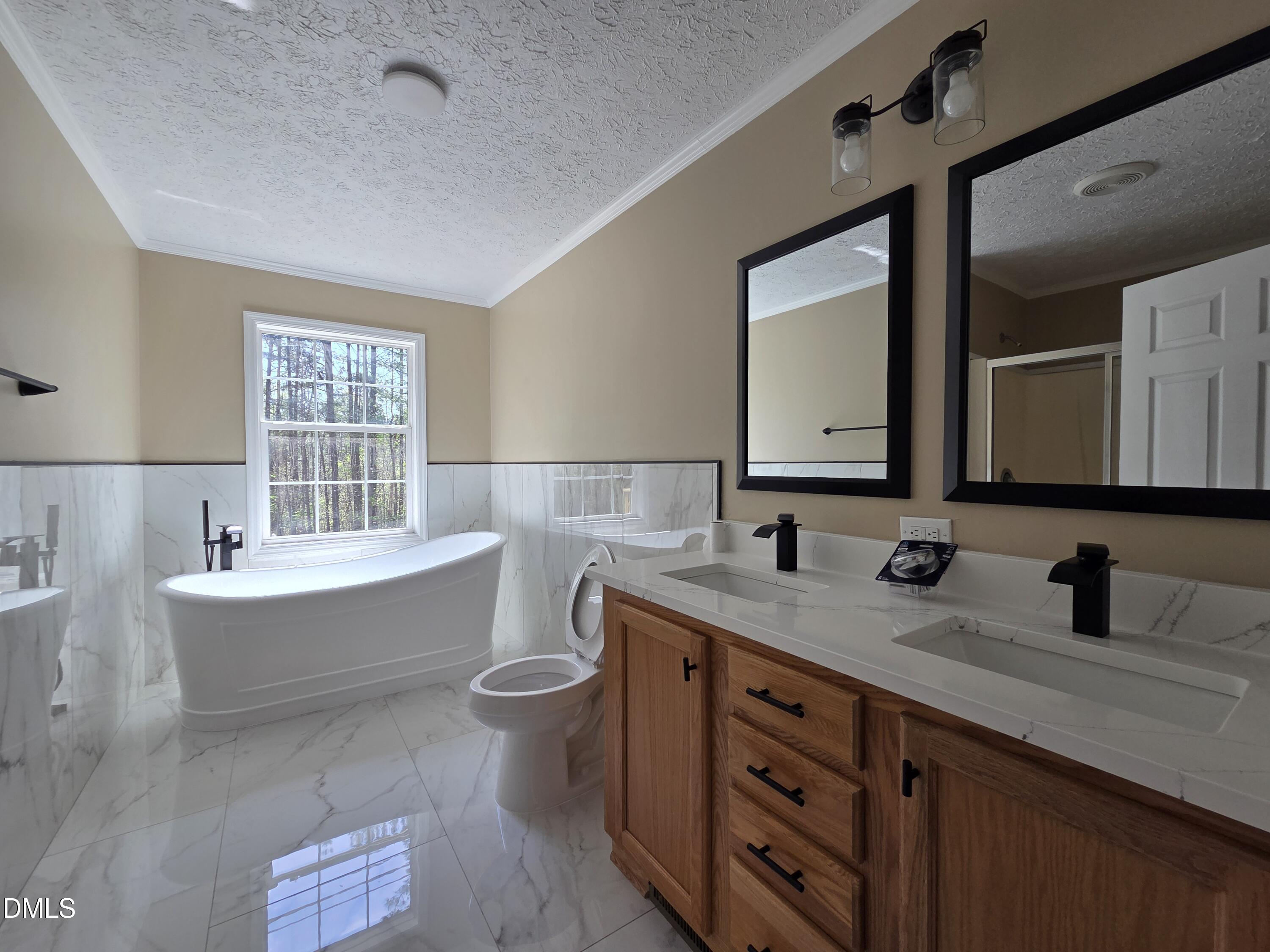 664 Glebe Road Henderson, NC 27537 - Photo 28 of 44 a bathroom with a double vanity sink a mirror and a bathtub