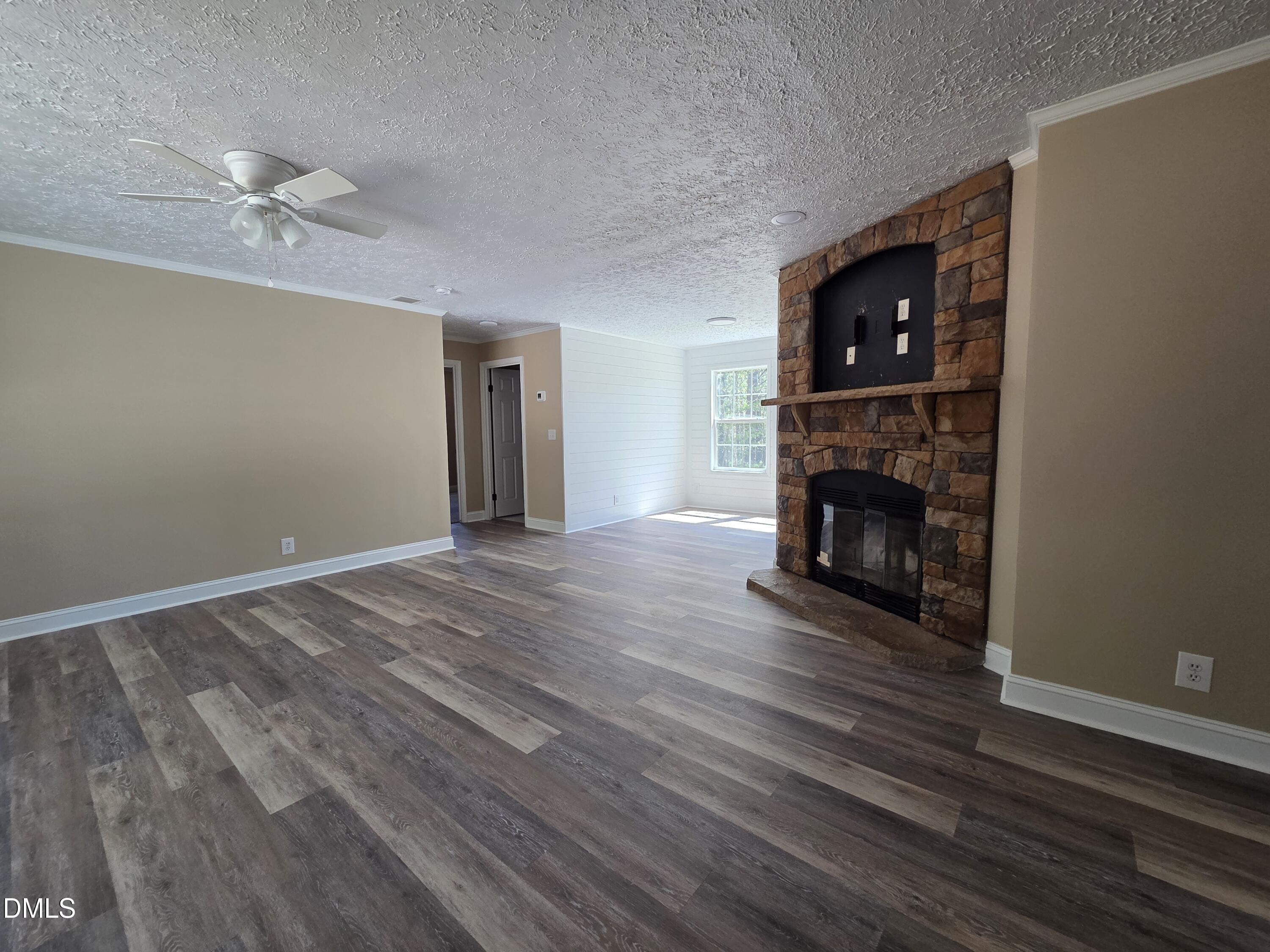 664 Glebe Road Henderson, NC 27537 - Photo 8 of 44 a view of empty room with wooden floor fireplace and fan