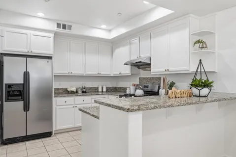a kitchen with stainless steel appliances granite countertop a sink a stove a refrigerator and cabinets