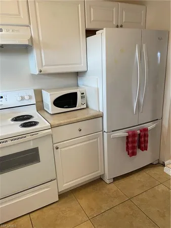 a kitchen with granite countertop white cabinets and white appliances