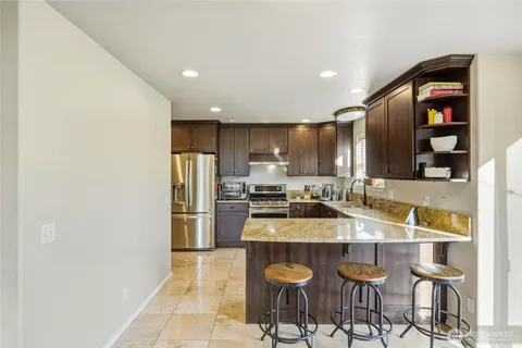 a kitchen with granite countertop a refrigerator and a stove top oven