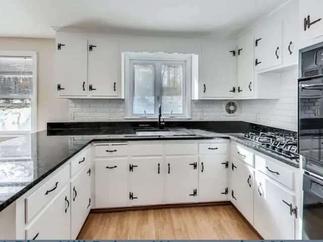 a kitchen with stainless steel appliances granite countertop a stove a sink and white cabinets