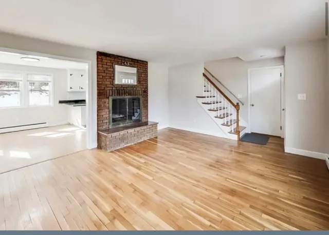 a view of an empty room with wooden floor and a window
