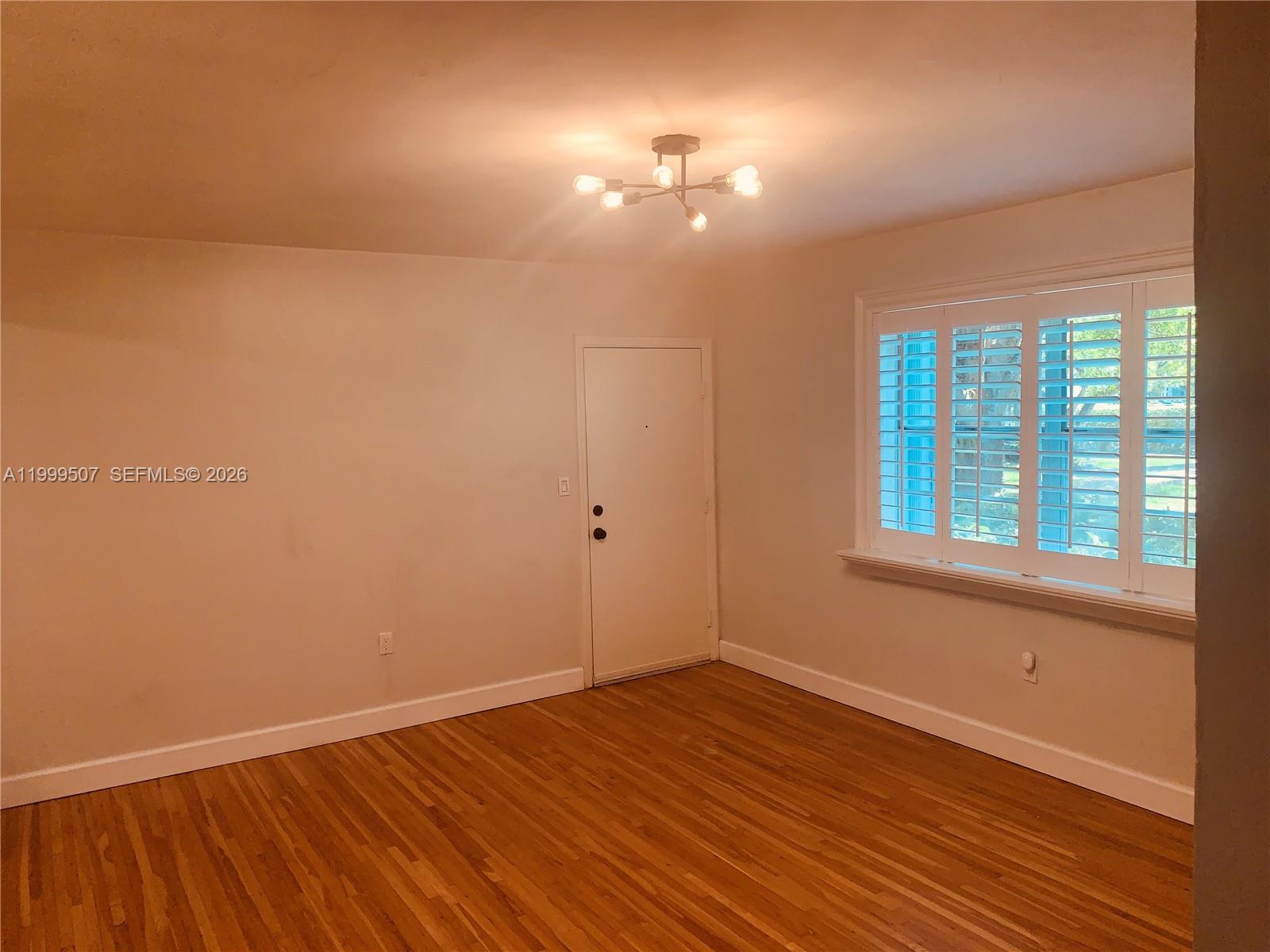 5605 Southwest 80th Street, Unit 97A Miami, FL 33143 - Photo 6 of 25 an empty room with wooden floor and windows