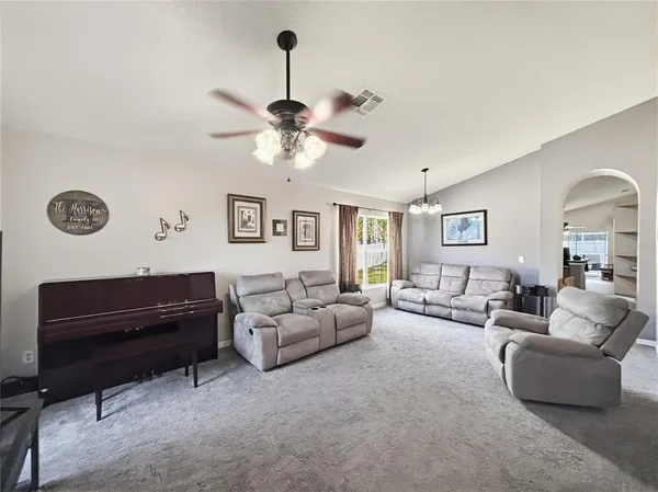 a living room with furniture ceiling fan and a wooden floor