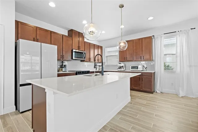 a kitchen with stainless steel appliances granite countertop a refrigerator a sink a stove and a oven