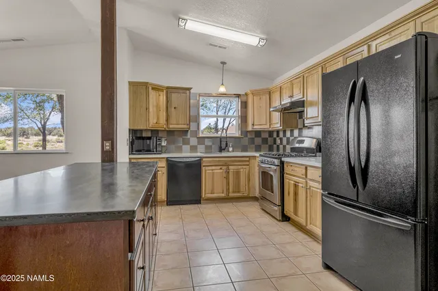 a kitchen with stainless steel appliances granite countertop a refrigerator a sink a stove and a refrigerator