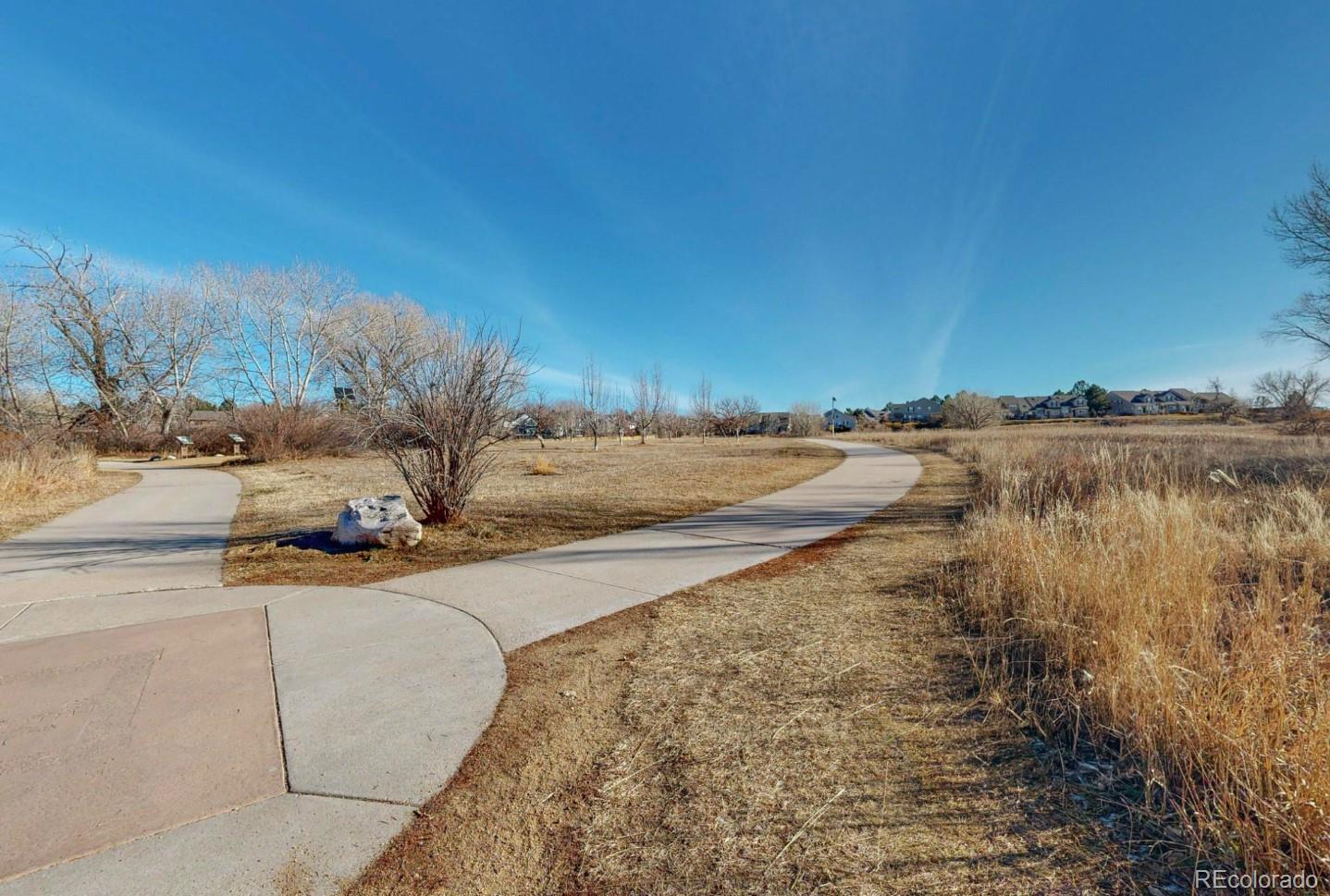 9195 Sugarstone Circle Highlands Ranch, CO 80130 - Photo 25 of 37 a view of a lake with beach and trees in the background