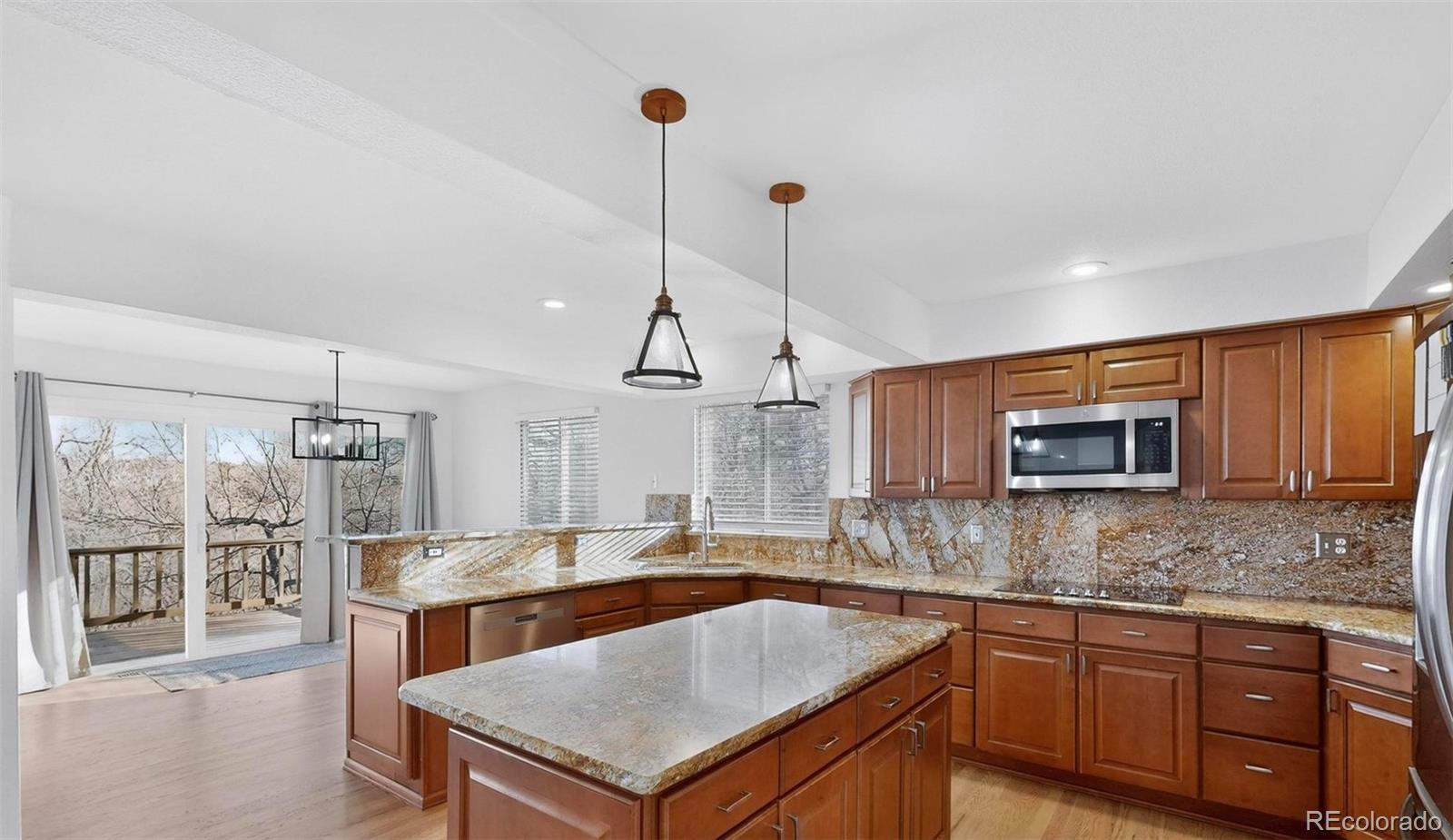 9195 Sugarstone Circle Highlands Ranch, CO 80130 - Photo 5 of 37 a kitchen with kitchen island granite countertop a sink a counter space appliances and cabinets
