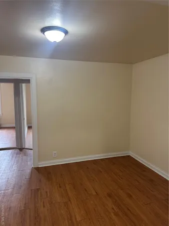 an empty room with wooden floor and next to a window