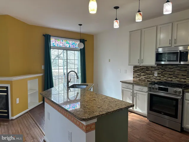 a kitchen with granite countertop a stove a sink dishwasher and a microwave with wooden floor