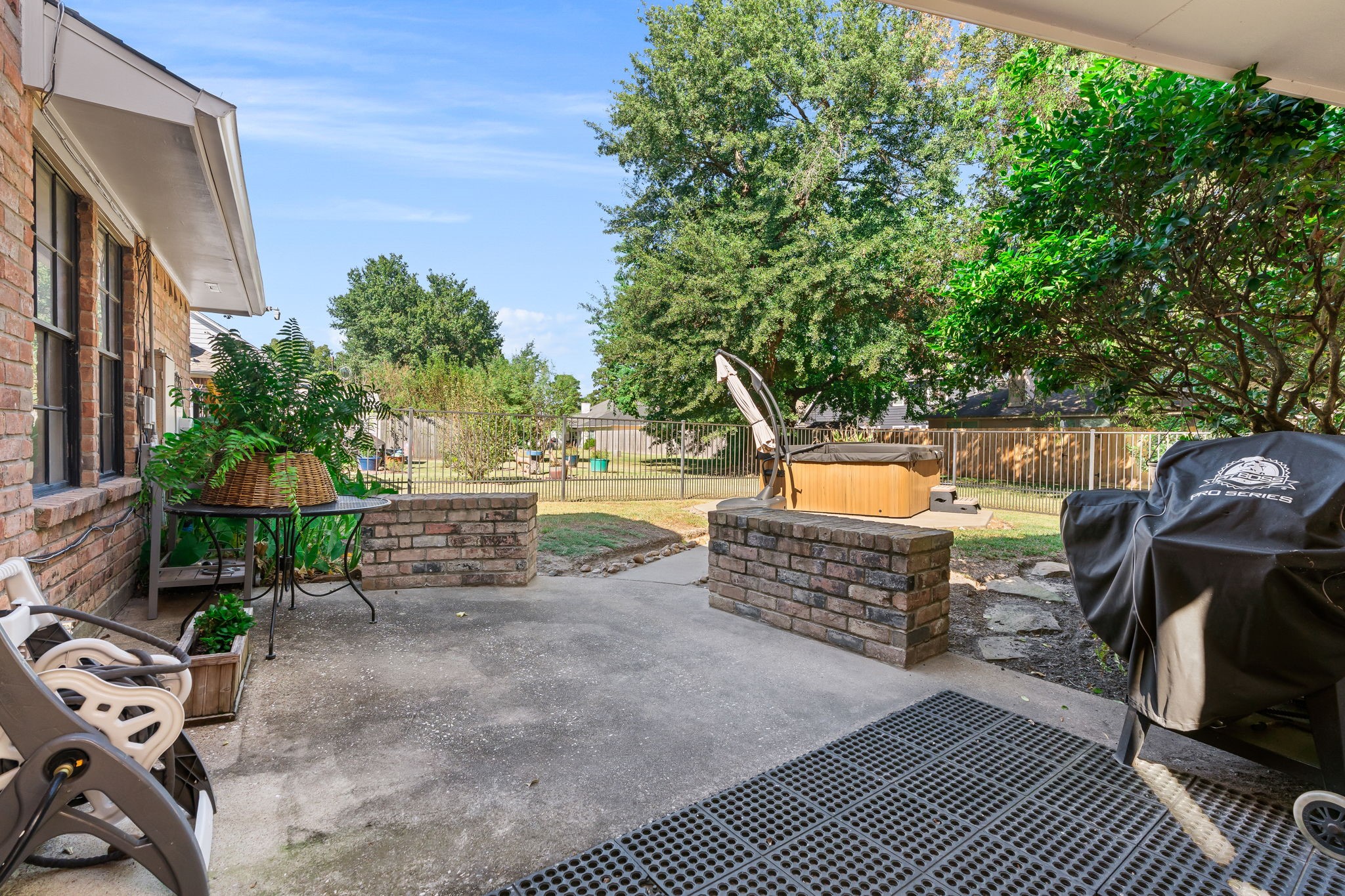 6971 Breezy Point Willis, TX 77318 - Photo 34 of 49 Looking into the yard from the patio. The hot tub stays. Iron fenced back yard. A convenient breezeway covers the walk way from home to the garage.