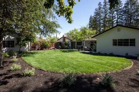 a backyard of a house with garden and outdoor seating