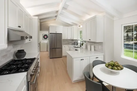 a kitchen with stainless steel appliances a sink a stove a refrigerator cabinets and dining table