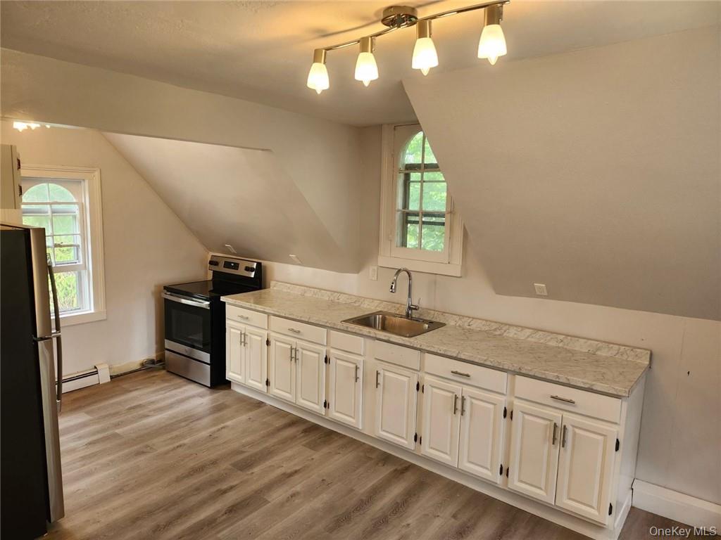a kitchen with granite countertop a sink cabinets stainless steel appliances and a window