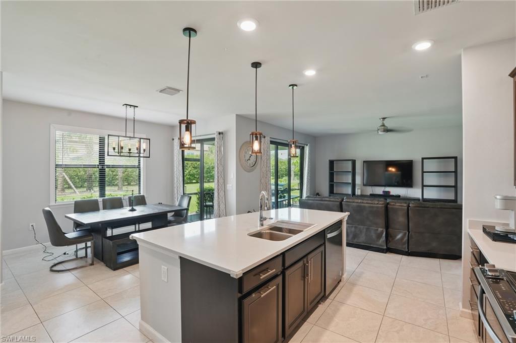 4934 Seton Way Ave Maria, FL 34142 - Photo 12 of 49 a large kitchen with kitchen island a large counter space a sink appliances and a living room view