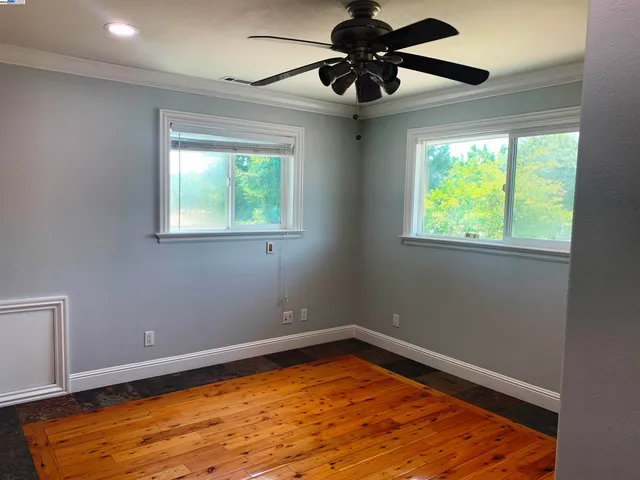 an empty room with a window and ceiling fan