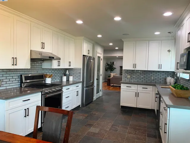 a kitchen with granite countertop white cabinets and stainless steel appliances